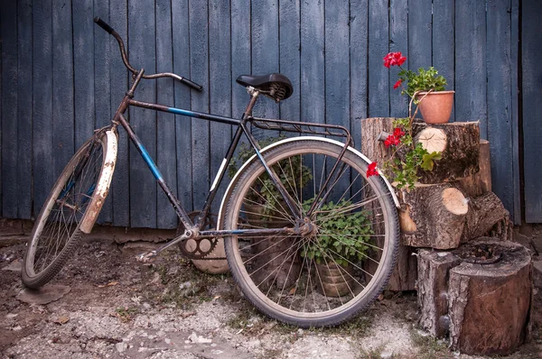 Old  bicycle near a blue wooden fence in village — Stock Photo, Image