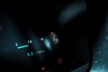 Aydınlatılmış uyarı ışıklarını ve loş aydınlatılmış bir aracın içindeki yakıt tüketim göstergelerini gösteren bir araç göstergesi.