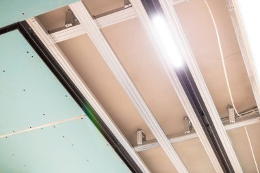 LED ışıklandırmanın yakın plan görüntüsü, inşaat altında açık metal çerçeve ve kablolarla askıya alınmış tavan raylarına entegre edildi.