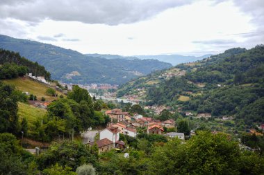 Dağ köyünün güzel panoramik manzarası Mieres Asturias İspanya yeşil tepeler ve bulutlu gökyüzü ile çevrili