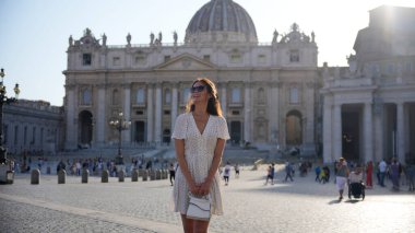 Bir gezgin, kültür tarihi ve mimarisi ile çevrili yumuşak akşam ışığı altında Temmuz ayında Vatikan 'daki Aziz Peter Meydanı' nı keşfediyor. 
