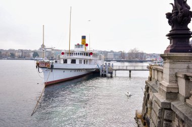 Rıhtımda kentin mimarisi ve sakin gölü ile kenetlenmiş eski bir vapurun editörel görüntüsü. 