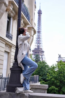 Paris 'te Eyfel Kulesi' nin yanındaki sokakta eğlenen neşeli genç kadın.