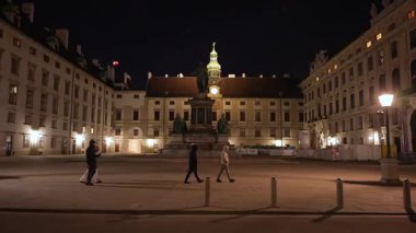 Viyana 'daki Hofburg Sarayı meydanının akşam görüntüleri. Noel zamanı aydınlanmış tarihi binalar arasında yürüyen insanlar.