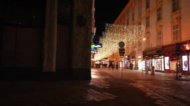 Avusturya, Viyana 'da yayınlanan video görüntüleri. Michaelerplatz yakınlarındaki bir alışveriş caddesinin akşam manzarası. Şenlikli Noel ışıkları binaları ve vitrinleri aydınlatıyor. Sadece editör kullanımı.