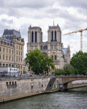 Notre Dame Katedrali ve Paris 'teki Seine Nehri restorasyon sırasında bulutlu bir yaz gününde gökyüzünün altında vinçle görünür hale gelir..