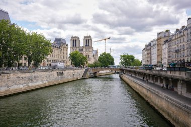 Paris 'te bulutlu yaz gökyüzünün altında Notre Dame Katedrali ve Paris binaları ile Seine Nehri' nin geniş manzarası