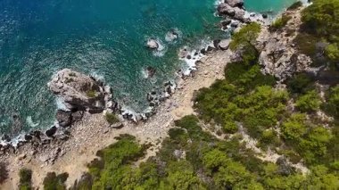 Yeşil kıyı ve temiz mavi su manzarası.