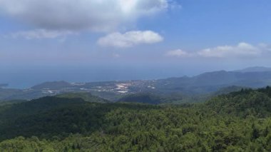 Mavi gökyüzünün altındaki ormanlık tepelerin insansız hava aracı görüntüleri.