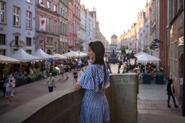 Gdansk Polonya 10 Eylül 2023 Köprüde kadın turist Old Town 'da Dlugi Targ sokak pazarını seyrediyor gün batımında kalabalık ve kafelerle