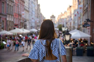 Polonya 'nın Gdansk kentindeki işlek cadde pazarının üstündeki yaya köprüsündeki genç bir kadının altın saat yolculuk yaşam tarzı