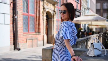 Güneş gözlüklü ve çizgili elbiseli, tarihi Gdansk Polonya 'lı genç turist kadın.