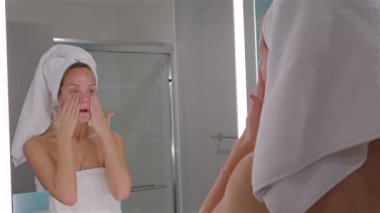 Genç bir kadın taze parlayan cilt için yüz temizleyicisini suyla yıkıyor. Sabah güzellik programının bir parçası.