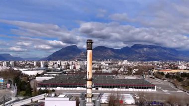 Kentsel ve çevresel karşıtlığı vurgulayan endüstriyel altyapı bacaları ve dağlarının hava insansız hava aracı görüntüsü