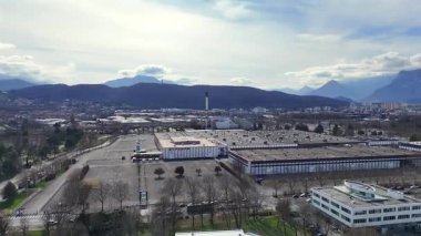 Grenoble 'ın panoramik drone görüntüsü açık gökyüzü altında modern şehir mimarisini ve Alp dağlarını gösteriyor