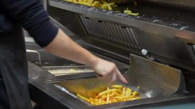 Sokak mutfağında profesyonel fritözde patates kızartması pişirmek.