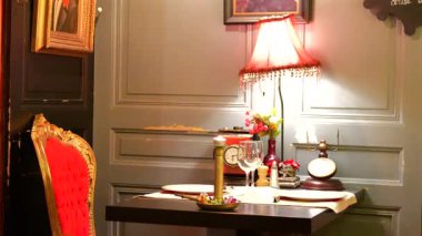 Sıcak lamba, kırmızı kadife sandalye ve antika dekorlu romantik bir restoran masası.