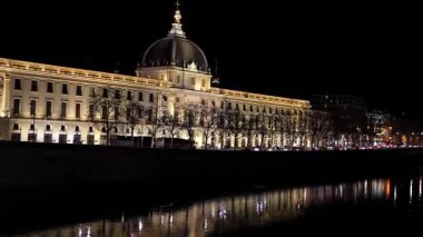 Lyon 'daki Hotel Dieu' nun tarihi şehir atmosferinde nehir yansımaları ve şehir ışıklarıyla gece görüntüsü.