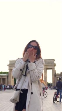 Brandenburg Kapısı yakınlarındaki trençkotlu neşeli kadın bahar günü Berlin 'de