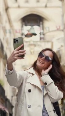Bordeaux Fransa 'nın dar tarihi caddesinde selfie çeken gülümseyen kadın.