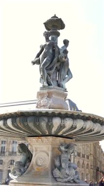 Bordeaux France tarihi taş çeşmesi güneşli bir günde şehir meydanında bronz heykeller ve 27 Mar 2025 'in arkasındaki eski binalar.