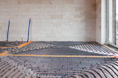 Yeni bir binanın izolasyon katmanına döşenmiş zemin altı ısıtma sistemi boruları. Beton kaplama, enerji tasarruflu ev inşaatı konsepti. Yüksek kalite fotoğraf