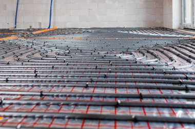 Yeni bir binanın izolasyon katmanına döşenmiş zemin altı ısıtma sistemi boruları. Beton kaplama, enerji tasarruflu ev inşaatı konsepti. Yüksek kalite fotoğraf