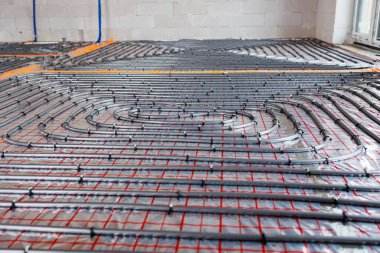 Yeni bir binanın izolasyon katmanına döşenmiş zemin altı ısıtma sistemi boruları. Beton kaplama, enerji tasarruflu ev inşaatı konsepti. Yüksek kalite fotoğraf