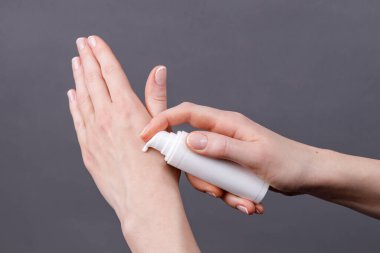 Kadın ellerine yakın plan beyaz şeker şişesinden cilde nemlendirici krem sürerek kişisel bakım ve hijyene odaklanıyor..