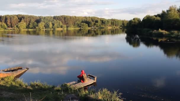 湖の近くのビーチに座っているカモメを見ている男 — ストック動画