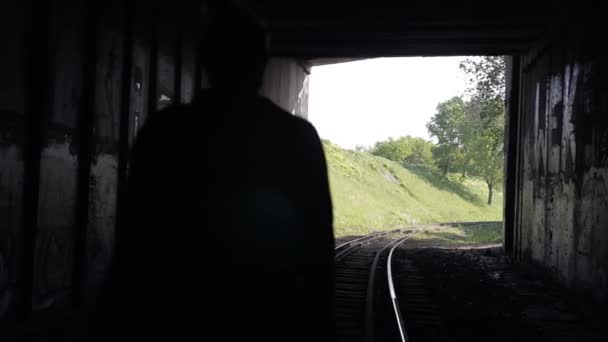 De man gaat in een tunnel op railroad tracks — Stockvideo