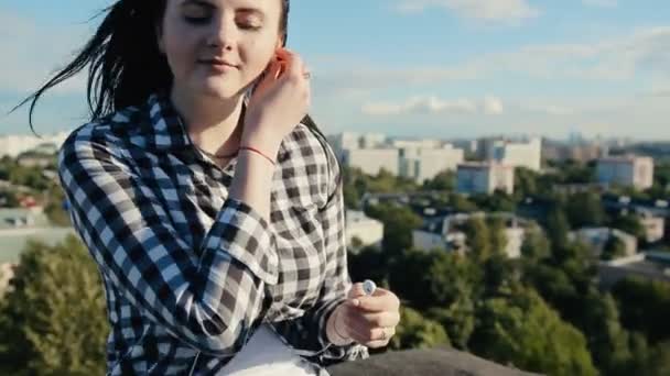 Dívka, posloucháte hudbu se sluchátky na střeše — Stock video