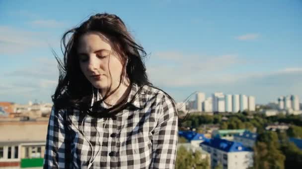 Девушка слушает музыку с наушниками на крыше — стоковое видео