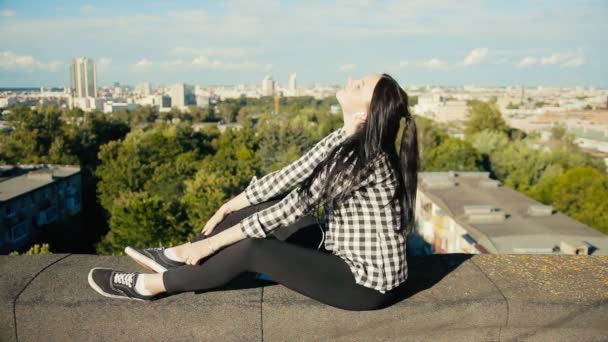 Chica escuchando música con auriculares en el techo — Vídeos de Stock