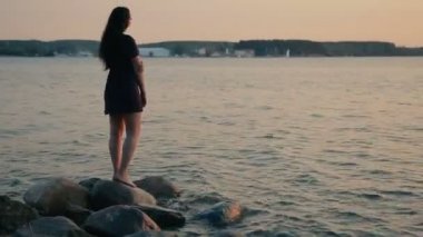Kız mesafe içine gün batımında sahilde görünüyor