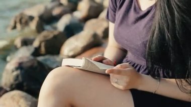 Kız sahil ve bir kitap okuma oturur