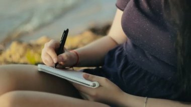 kadın'ın kıyısında oturan bir defter not alma