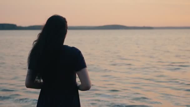 Menina fotografando o pôr do sol, de pé na costa — Vídeo de Stock