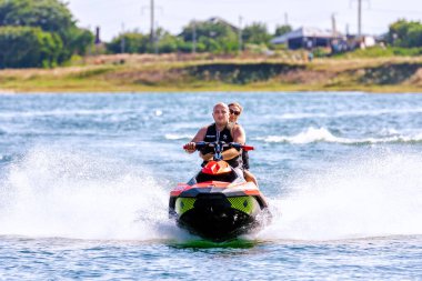 Krasnodar, Rusya - 25 Temmuz 2020: Güneşli yaz gününde arka koltukta bir kadınla jet ski şoförü