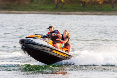 Krasnodar, Rusya - 25 Temmuz 2020: Güneşli yaz gününde arka koltukta neşeli bir kadınla jet ski şoförü
