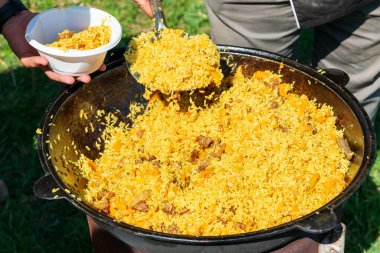 Lezzetli pilav salatası olan büyük kazan güneşli bir günde dışarıda piknik yapıyor.
