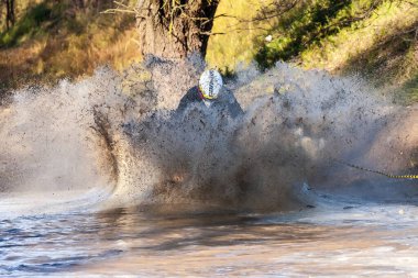 Afipsip, Rusya - 31 Ekim 2020 BRP Can-Am miğferli bisikletli sporcu Mud Racing yarışmasında suya su sıçratıyor. ATV motosiklet yarışmaları - popüler ekstrem spor ve açık hava aktiviteleri