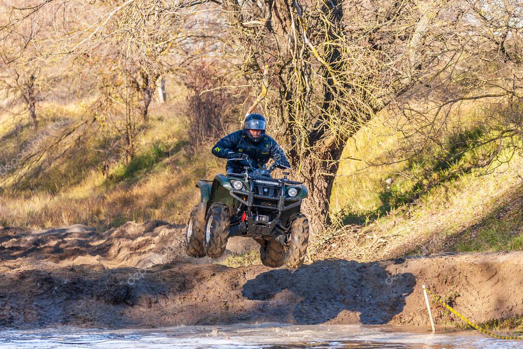 Afipsip, Russia - October 31, 2020: Sportsman on quad bike jumping into water at Mud Racing contest. ATV motobike competitions is popular extreme sport and outdoor activity