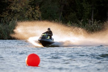 Krasnodar, Rusya - 24 Ekim 2020: Jet ski yarışçısı Güney Rusya Aquabike Şampiyonası 'nda yarışırken günbatımında su sıçrayan bir su aracını sürüyor.