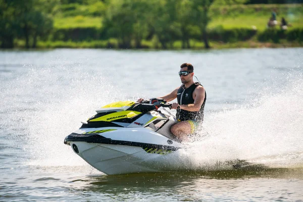 Krasnodar, Rusya - 25 Temmuz 2020: BRP Sea-Doo jet kayak su aracı sürücüsü güneş batarken nehir kıyısında yüksek hızda su bisikleti sürüyor. Aktif yaz tatili konsepti
