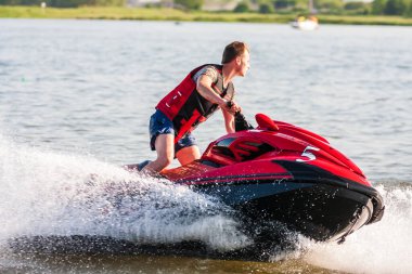 Krasnodar, Rusya - 25 Temmuz 2020: Nehir kıyısında gün batımında su bisikleti süren jet ski şoförü. Ekstrem sporlar ve aktif yaz tatili konsepti