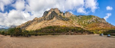 Beautiful scenic sunny blue sky with clouds landscape of Yuzhnaya Demerdzhi rocky mountain in Crimea, Ukraine called Dolina Privideniy, or Ghost Valley. Wide angle panorama of Demerdji mountain clipart