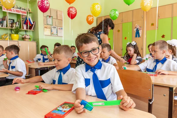 Krasnodar, Rusya - 1 Eylül 2020: İlkokul eğitimine başlama tatilinde okul sıralarında birinci sınıf öğrencileri. Birinci sınıftaki mutlu çocuklar.