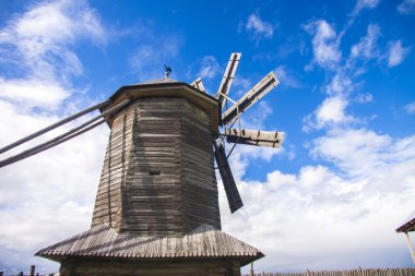 Wooden windmill on cloudy sky background