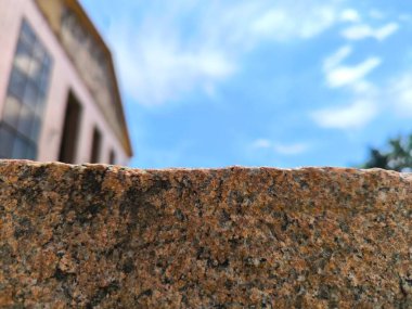 Kırmızımsı granit yüzeyin yakın plan çekimleri. Arka planda bulanık bir bina var.